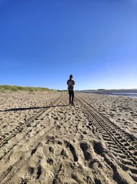 Rear view of man standing on sand