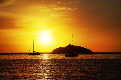 Silhouette sailboats in sea against sky during sunset