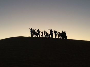 Silhouette people on desert against clear sky