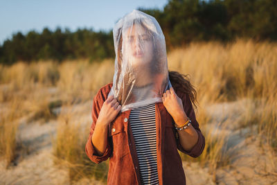 Young woman with face covered by plastic bag standing at beach
