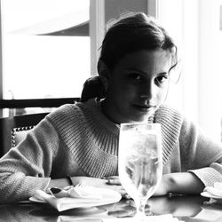 Portrait of teenage girl with drink glass at table in restaurant