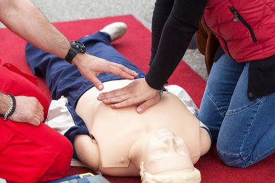 Midsection of paramedic practice with cpr dummy