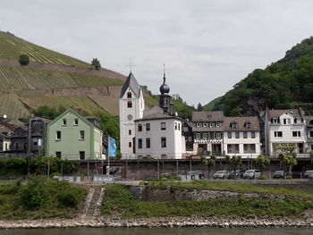 Houses by buildings against sky in city