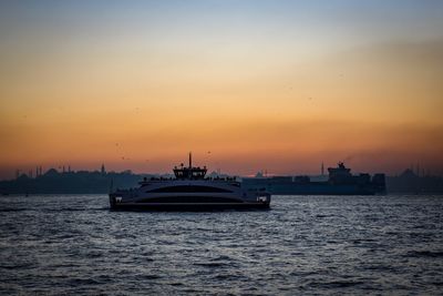 Silhouette of ship sailing in sea during sunset