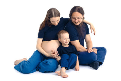 Portrait of happy family sitting on sofa against white background