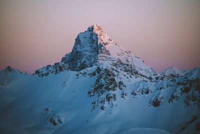 Scenic view of snowcapped mountains against clear sky during sunset