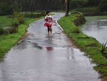 Full length of child on wet road during rainy season