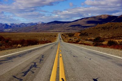 Road leading towards mountain against sky