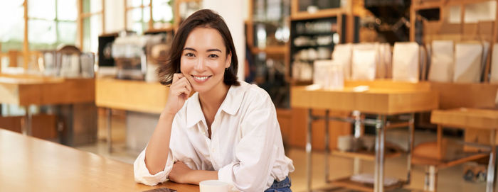 Portrait of young woman standing in cafe