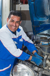 Portrait of smiling mechanic repairing car at auto repair shop