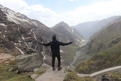 A young man enjoying the view of the valley and sky from the top of the mountains