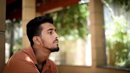 Profile view of young man with beard looking away outdoors