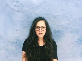 Portrait of young woman standing against wall