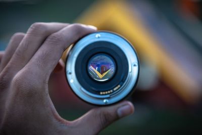 Cropped image of person holding camera lens while looking at tent