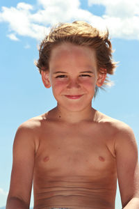 Portrait of happy shirtless boy against sky