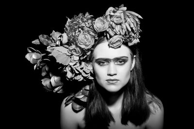 Portrait of fashion model wearing flowers against black background