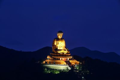 Gold colored buddha statue at po lin monastery against clear sky