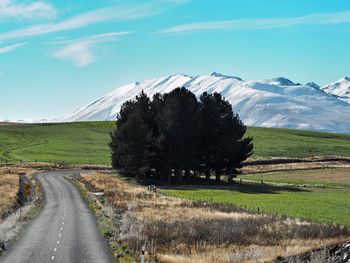 Road by agricultural field against sky