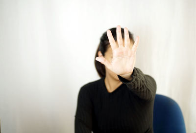 Woman covering face by gesturing against wall