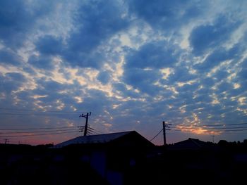 Silhouette houses and buildings against sky during sunset