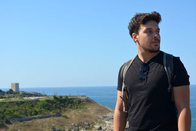 Mid adult man standing at beach against clear blue sky