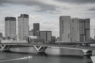 Bridge over river by buildings against sky in city