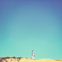 Full length of woman standing against clear blue sky