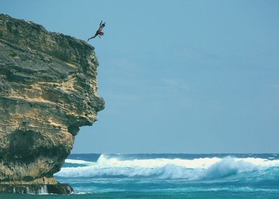 Low angle view of man jumping into water from the rock