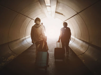 Rear view of people standing in illuminated tunnel