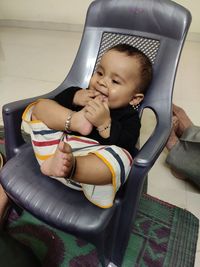 High angle view of cute girl sitting on sofa