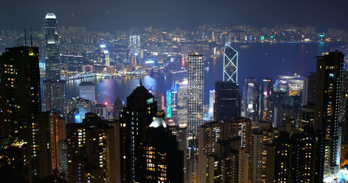 Aerial view of river amidst illuminated modern buildings at night