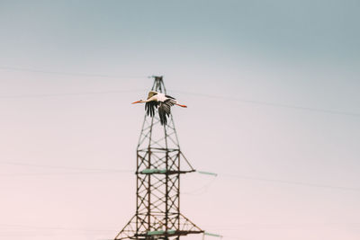 Low angle view of electricity pylon against clear sky