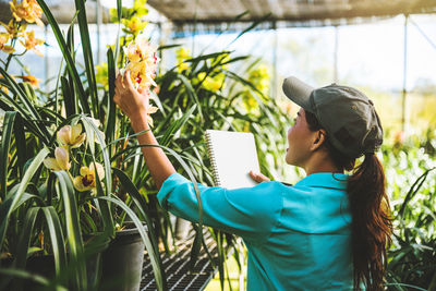 Female researcher examining flowers in greenhouse