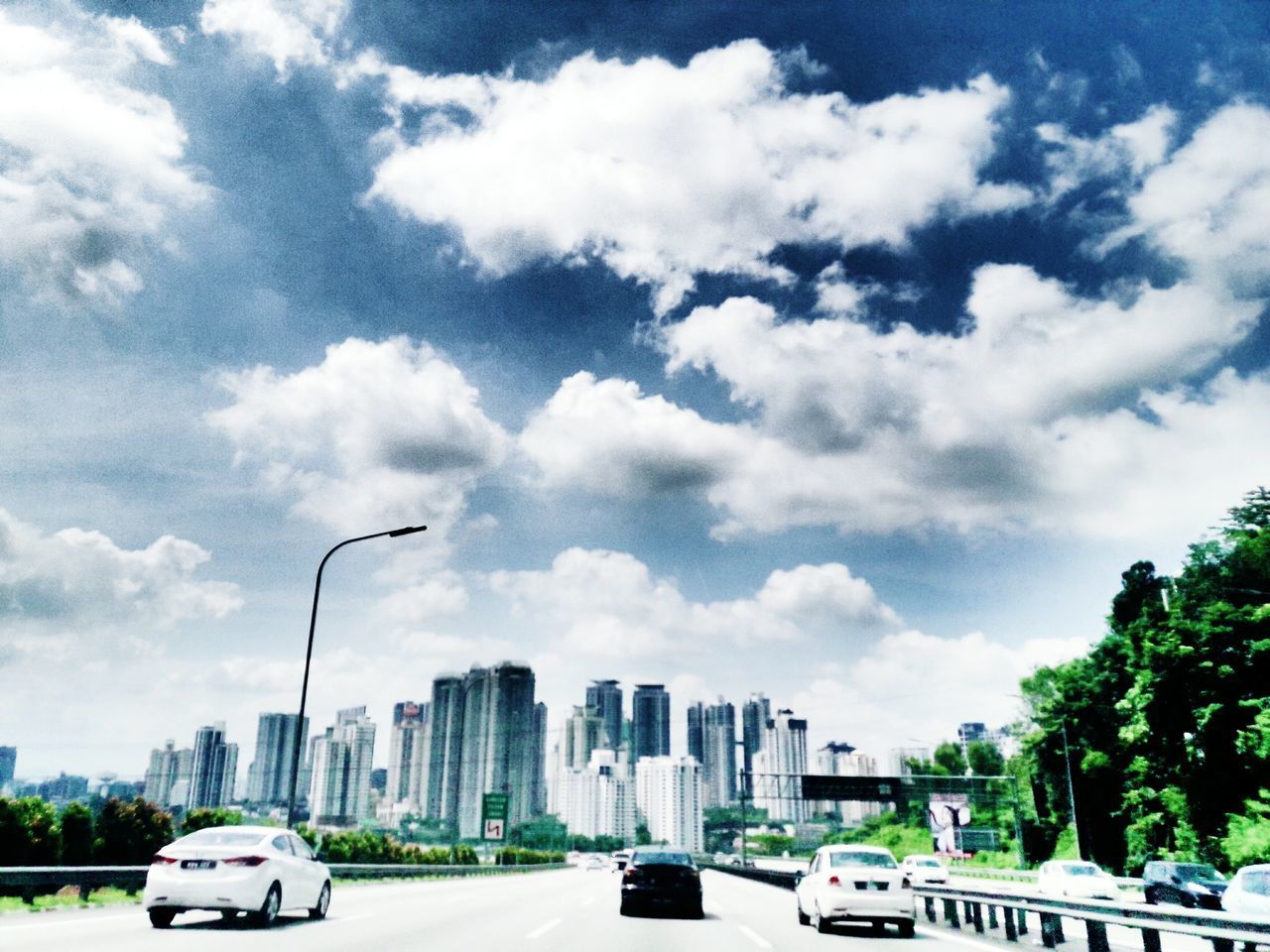 VEHICLES ON ROAD AGAINST CLOUDY SKY