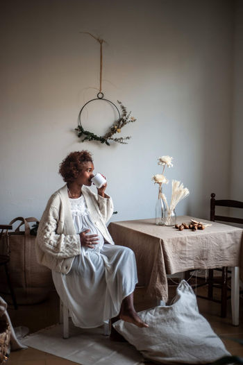 MIDSECTION OF WOMAN SITTING ON TABLE