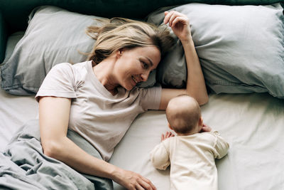 Mother using phone while lying on bed at home