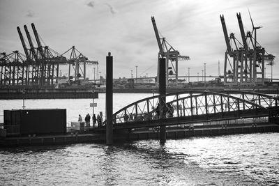 Cranes at commercial dock against sky