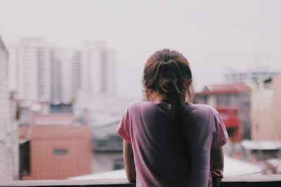 Rear view of woman standing against buildings in city