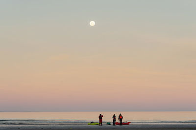 People on beach against sky during sunset