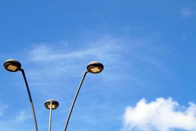 Low angle view of street lights against blue sky