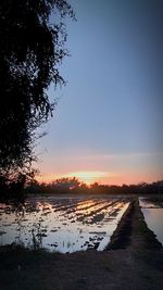 Scenic view of lake against clear sky during sunset