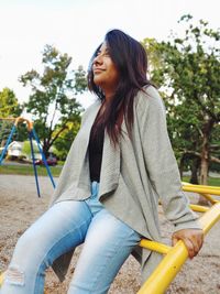 Young woman looking away while sitting on playground