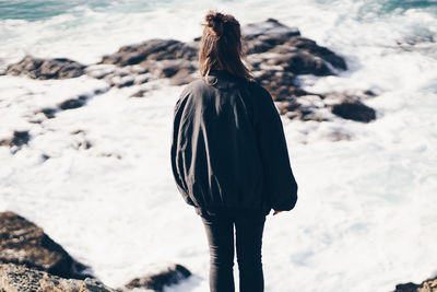 Rear view of woman standing on beach against sky
