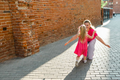 Portrait of woman standing against brick wall