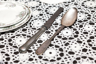 Tin spoon and knife on the table . ancient kitchen utensils . handmade embroidered tablecloth