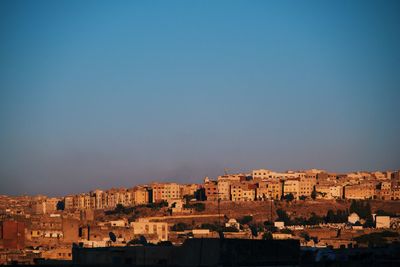 Buildings in city against clear blue sky