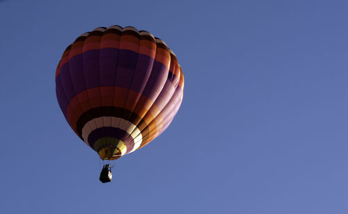 Low angle view of hot air balloons against clear blue sky