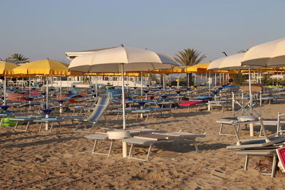 Chairs and tables on beach against sky