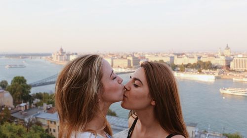 Lesbian couple kissing against cityscape