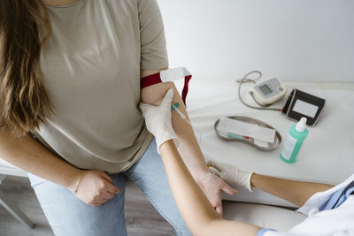 High angle view of doctor removing blood from patient's arm in clinic